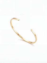 Brazalete ajustable en acero quirúrgico bañado en oro 18K, diseño minimalista unisex con acabado brillante.