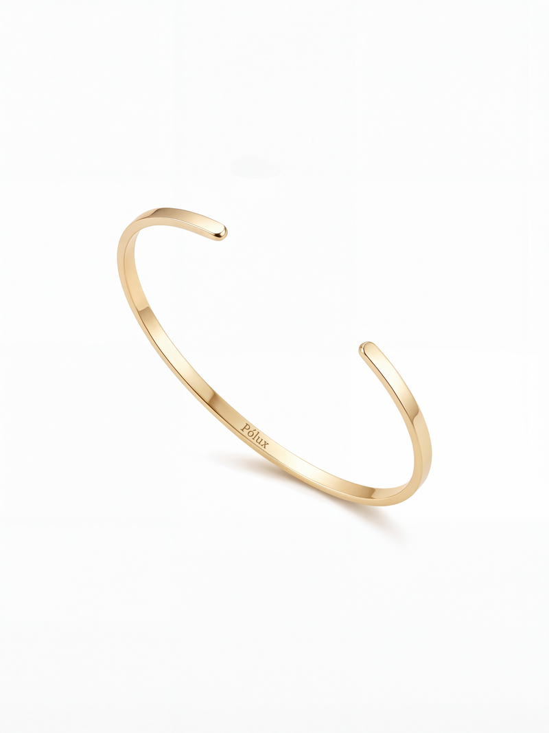 Brazalete ajustable en acero quirúrgico bañado en oro 18K, diseño minimalista unisex con acabado brillante.