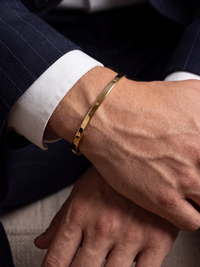 Detalle del brazalete unisex en acero quirúrgico enchapado en oro, ideal para muñecas de 16 a 19 cm.