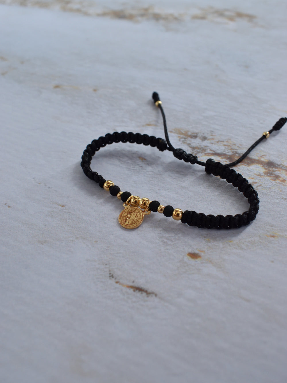 Pulsera de protección San Benito negra y dorada con empaque premium Pólux