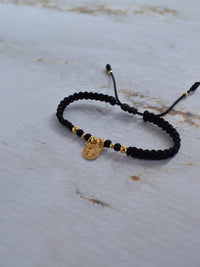 Pulsera de protección San Benito negra y dorada con empaque premium Pólux