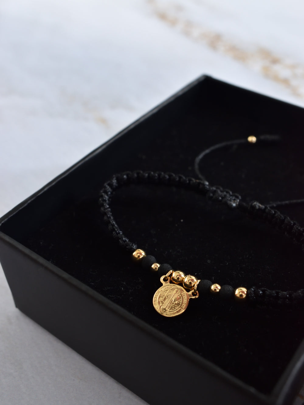 Pulsera unisex tejida en negro con contraste de balines dorados