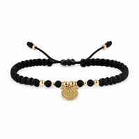 Pulsera San Benito tejida en macramé negro con oro laminado 18K sobre fondo blanco