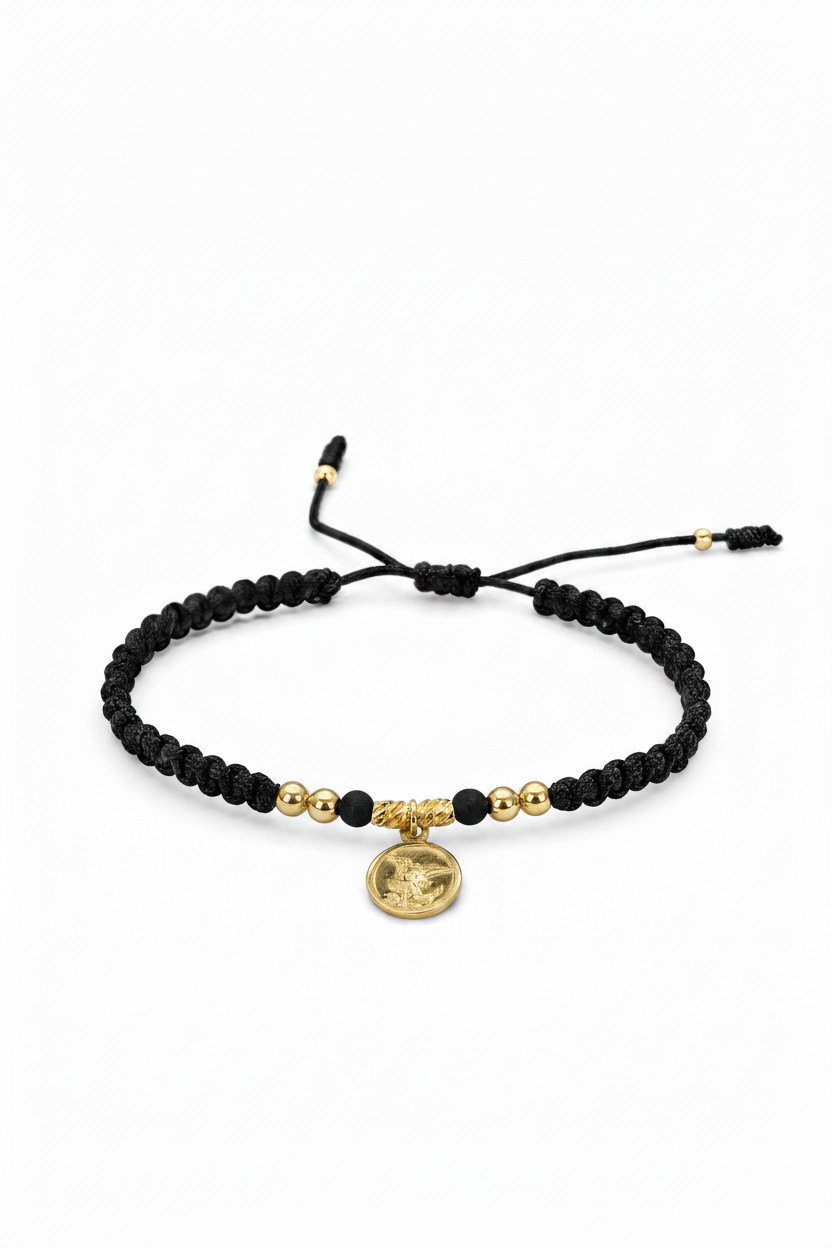 Pulsera San Miguel Arcángel tejida en macramé negro con oro laminado 18K sobre fondo blanco