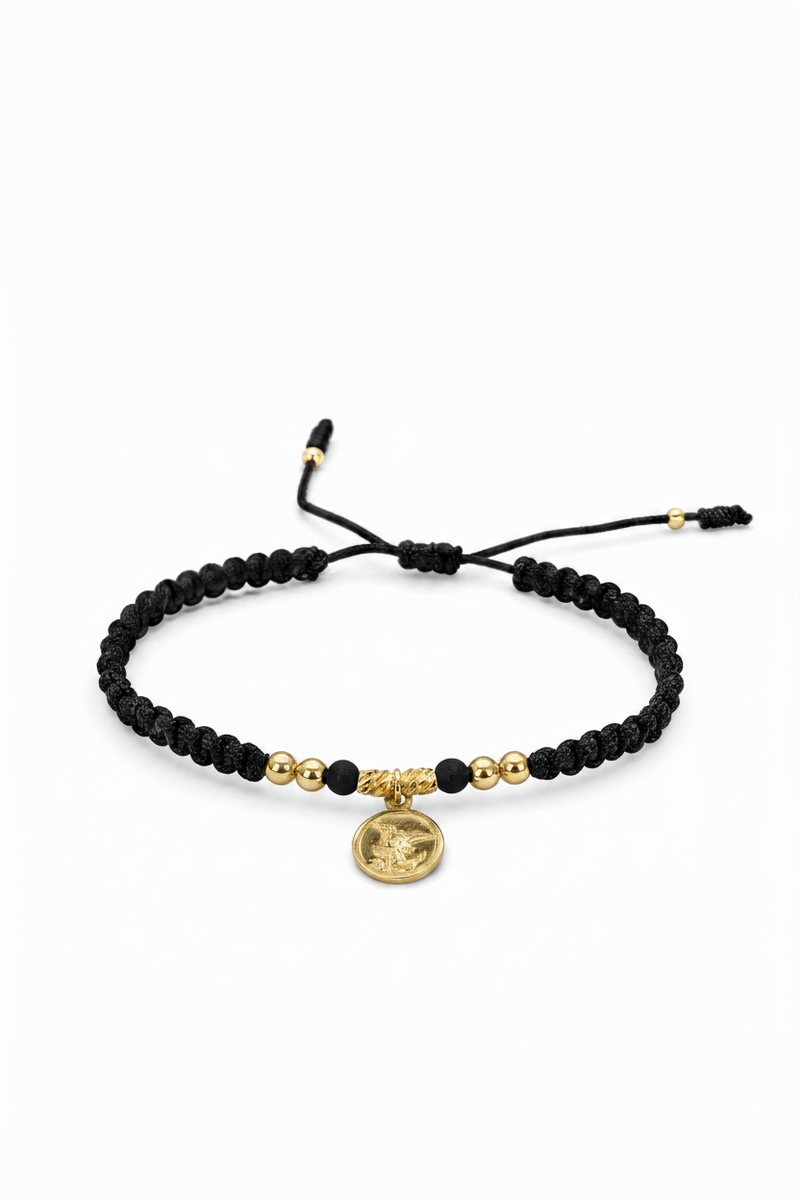 Pulsera San Miguel Arcángel tejida en macramé negro con oro laminado 18K sobre fondo blanco