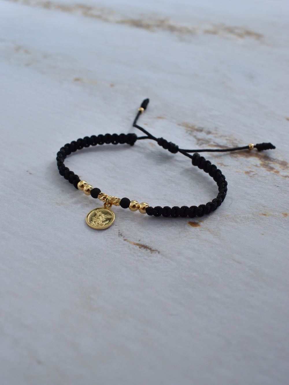 Pulsera San Miguel Arcángel tejida artesanalmente en macramé negro y oro 18K