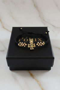 Detalle en ángulo del dije Tío Rico en oro laminado 18K sobre pulsera de macramé